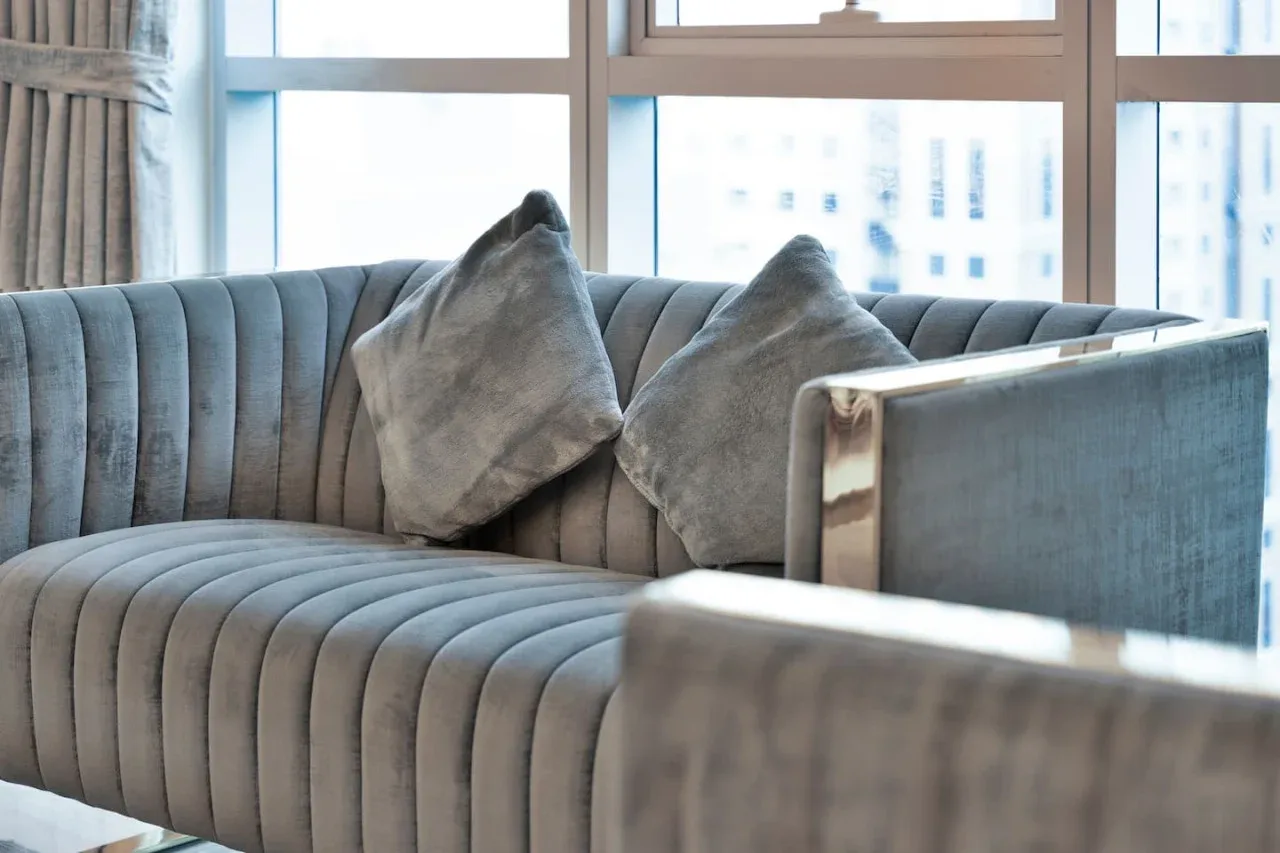 A living room seating area with a gray sofa in front of large windows.