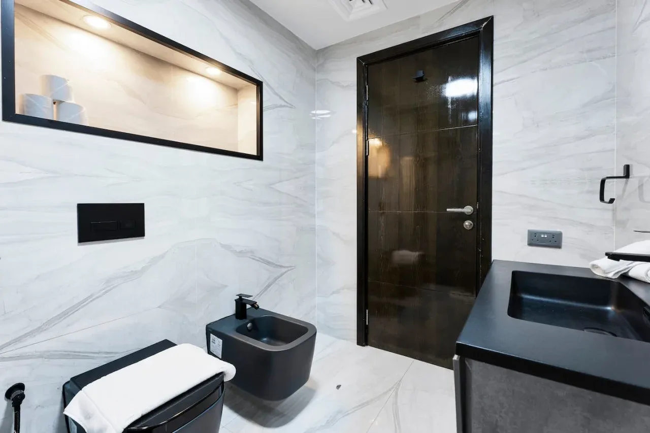 A tiled bathroom with a dark vanity, sink, and toilet.