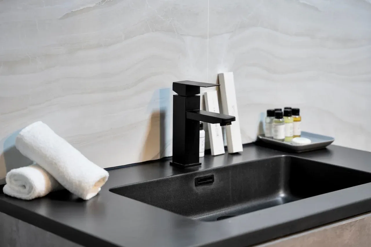 A modern bathroom vanity with a dark sink, faucet, and neatly arranged towels.