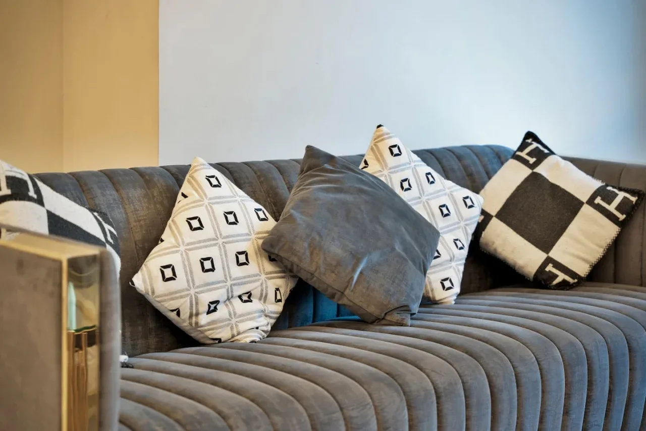 A living room seating area with a gray sofa and patterned cushions.