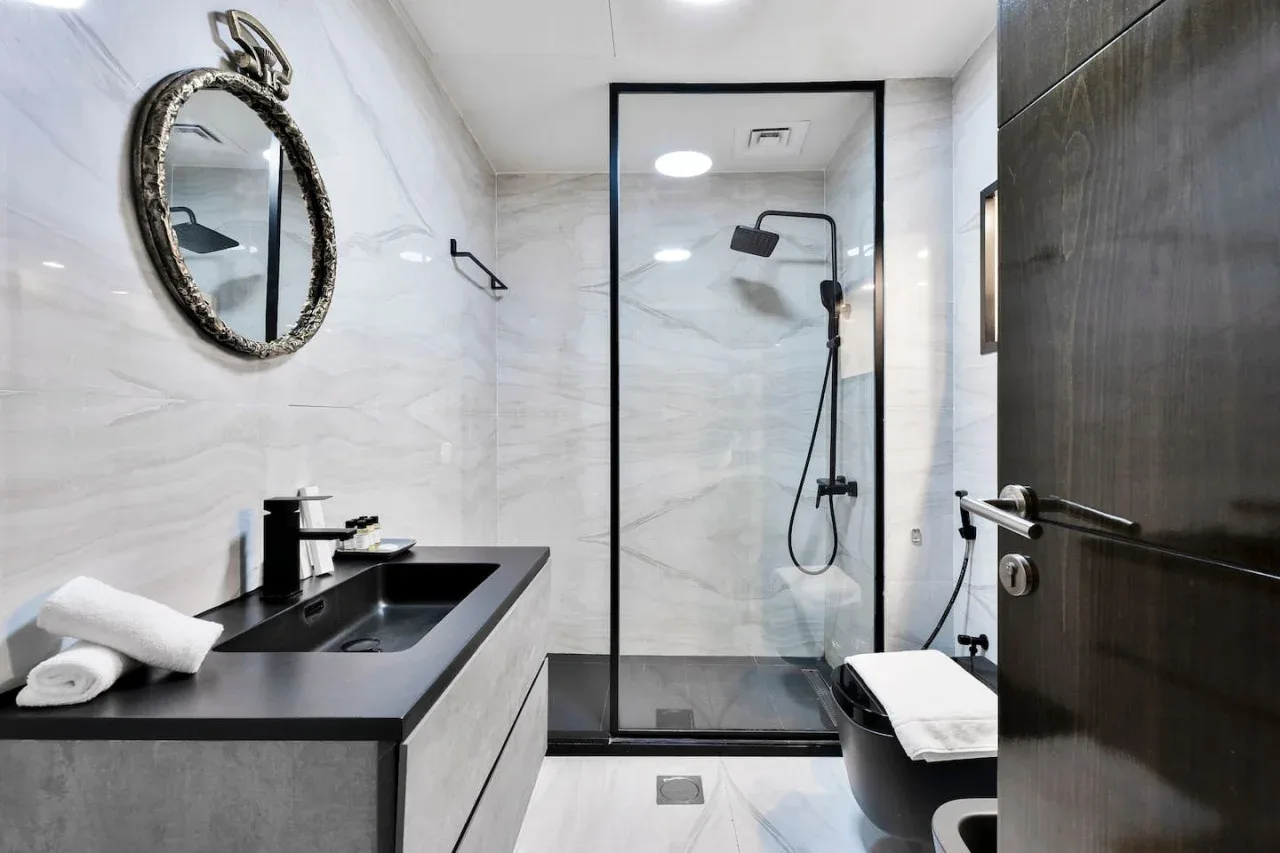 A modern bathroom with a dark vanity and a glass-enclosed shower.