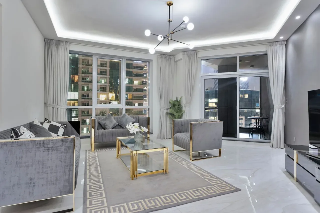 A bright living room with seating, a coffee table, and large windows.