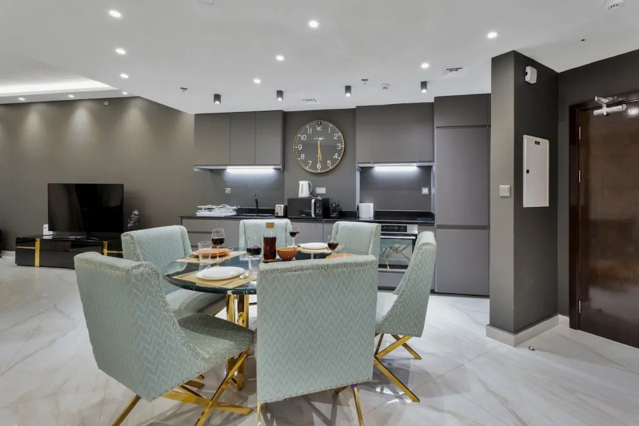 A modern dining area with a round table and a kitchen in the background.