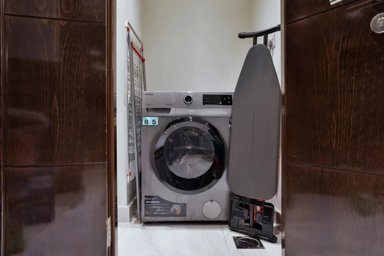 A laundry area with a front-loading washing machine and ironing board.