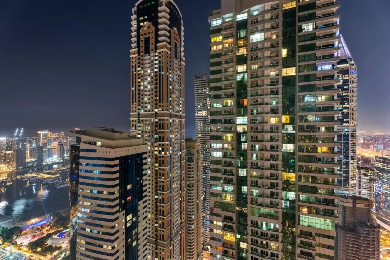 Nighttime cityscape with illuminated high-rise buildings and streets below.