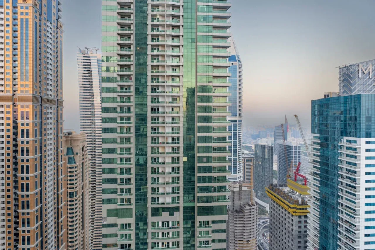 A city skyline with closely spaced high-rise buildings and a hazy horizon.