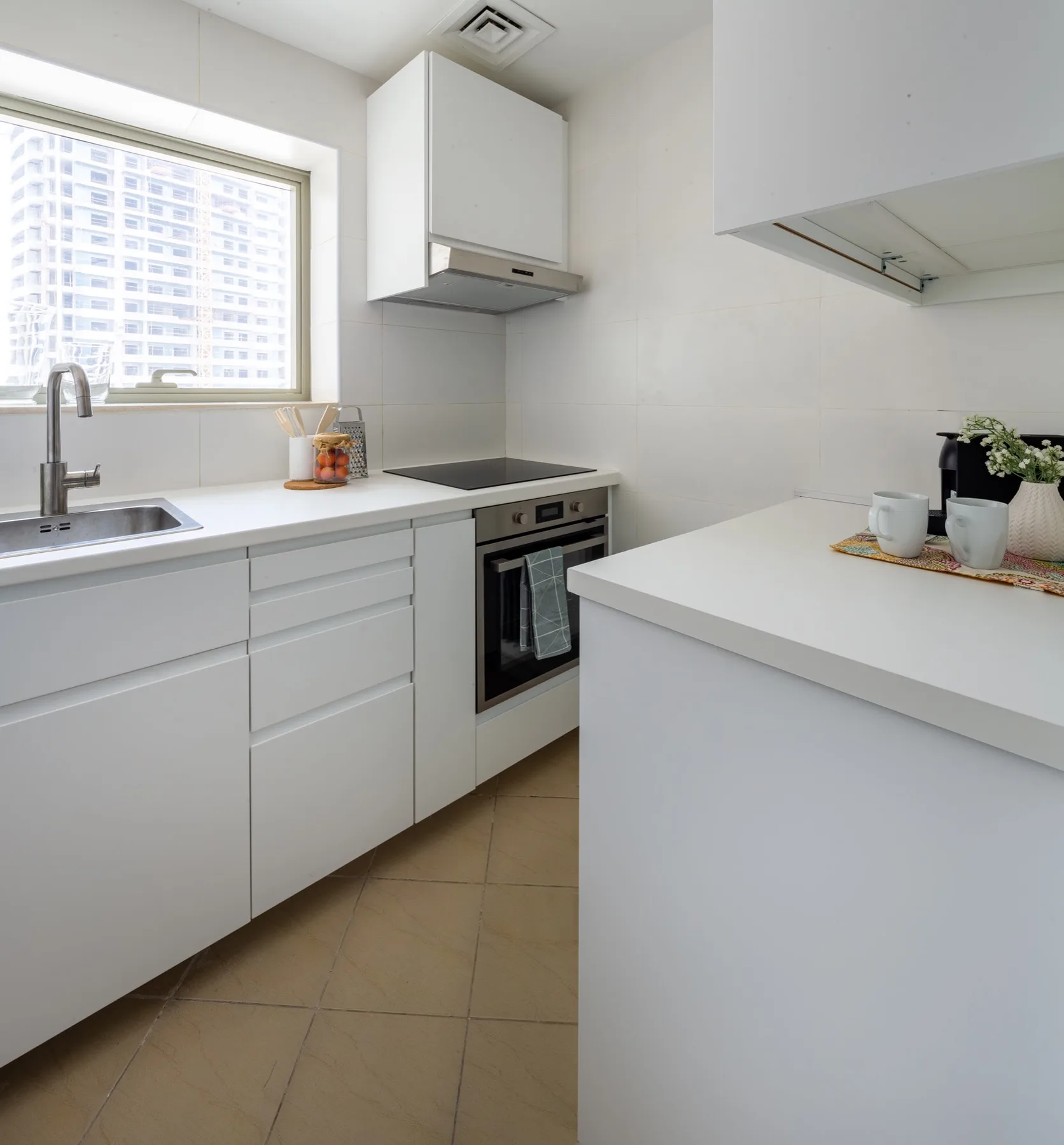 Una cocina luminosa con gabinetes blancos, fregadero y horno integrado.
