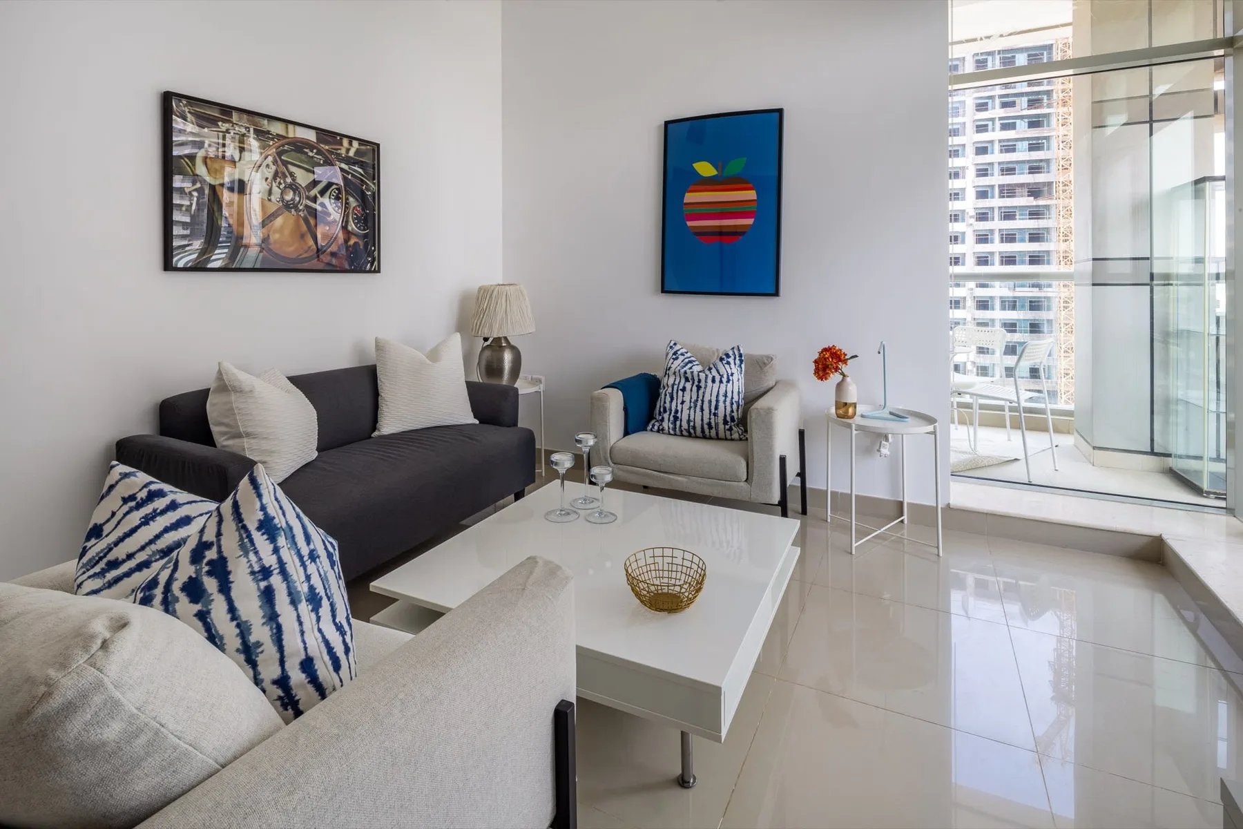 Una sala luminosa con asientos, una mesa de centro y ventanas grandes.