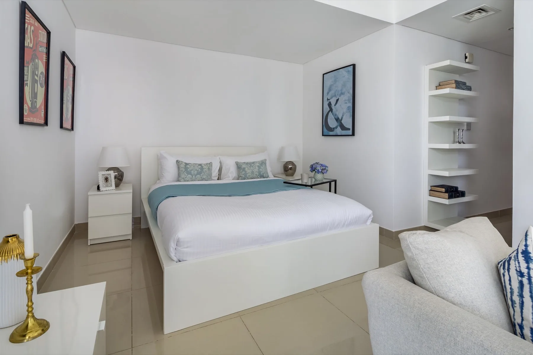 Un dormitorio luminoso con una cama tendida, mesitas de noche y estanterías abiertas.