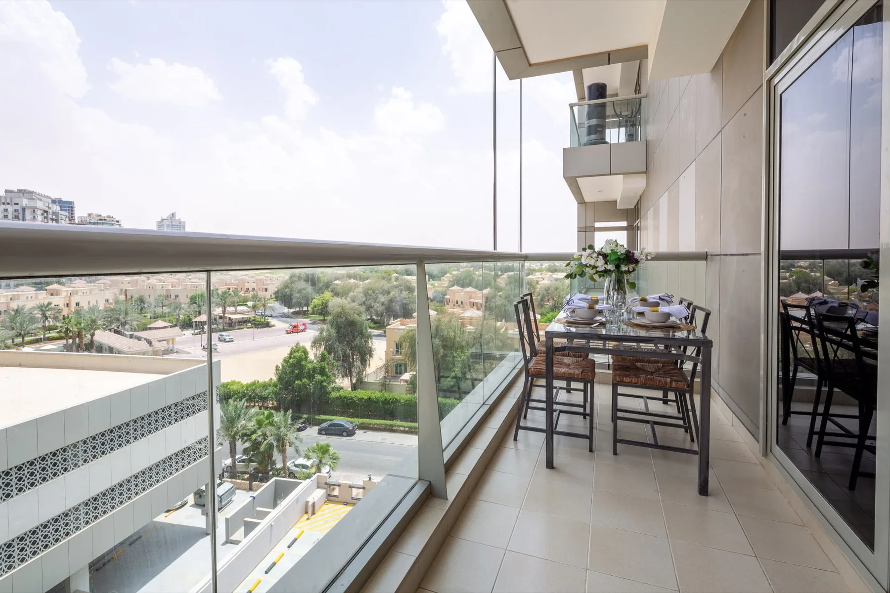 Un comedor en el balcón con mesa y asientos ofrece vistas al vecindario.
