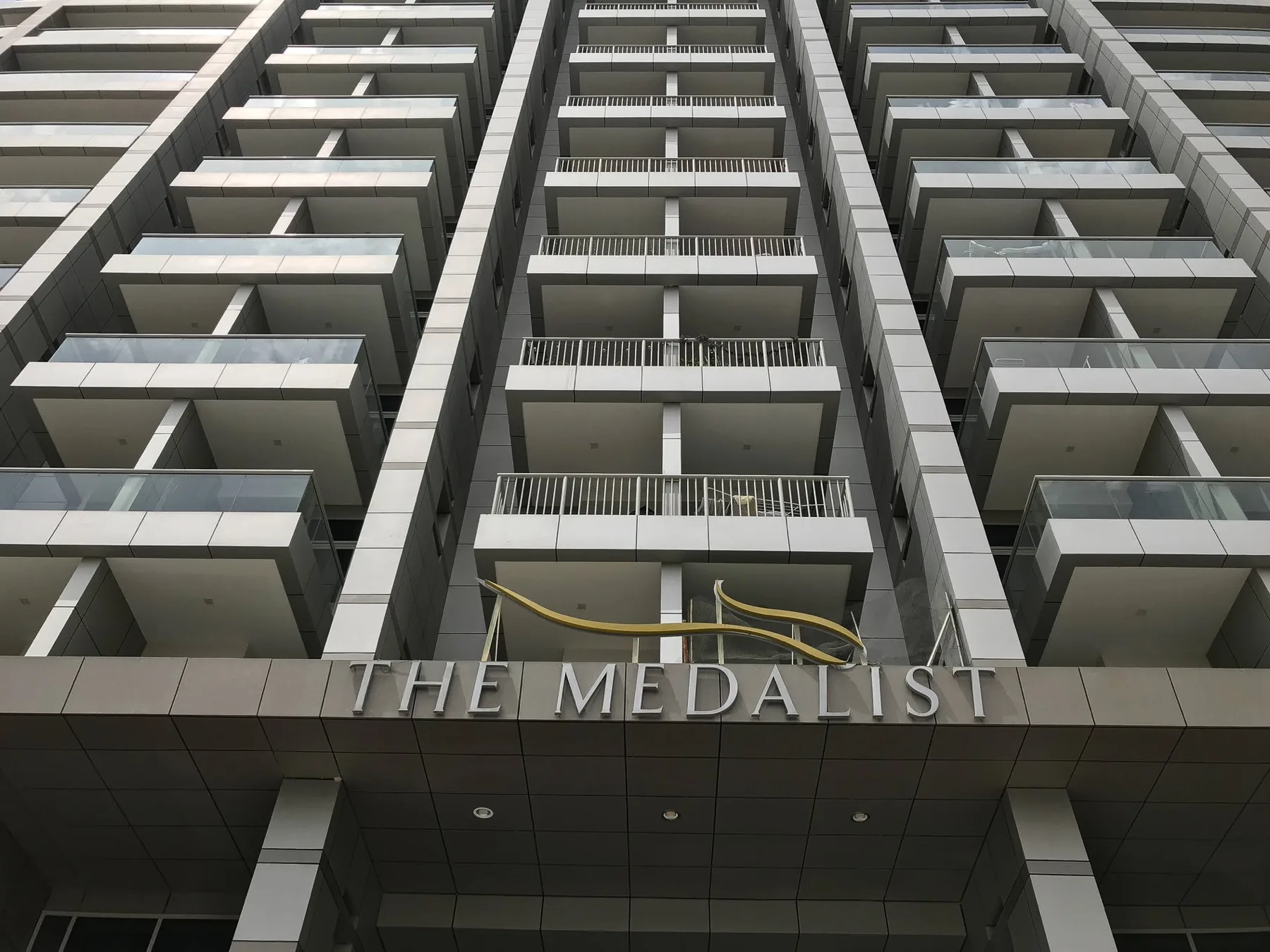 La fachada de un edificio alto con filas de balcones sobre un letrero.
