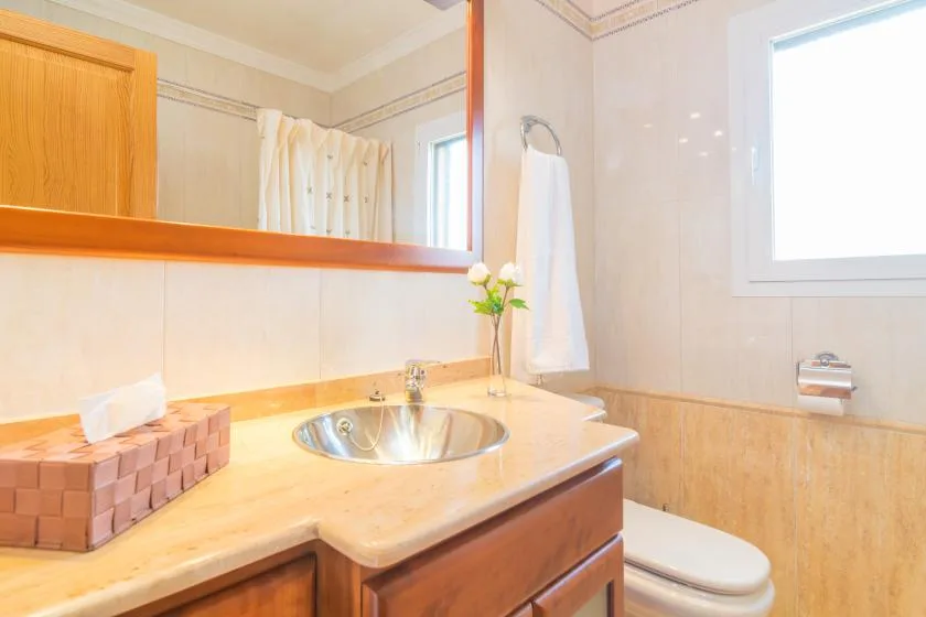 A bright bathroom with a sink, countertop, and toilet.