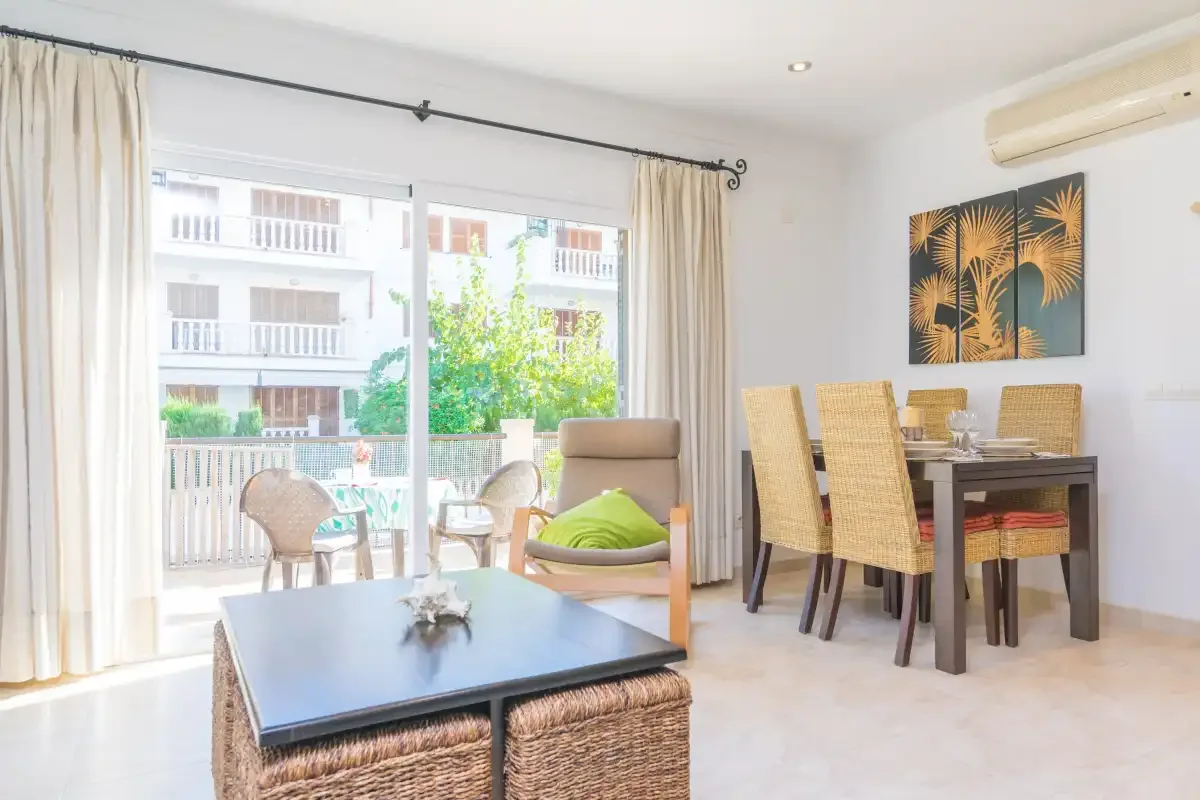 A bright dining and sitting area opens onto a balcony through large glass doors.