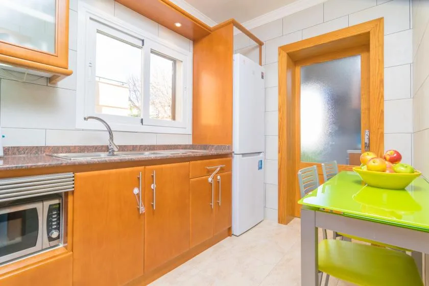 A bright kitchen with orange cabinets, a window, and a lime-green table.