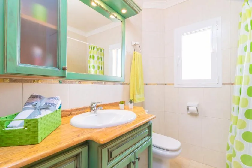 A bright bathroom with a sink vanity, toilet, and patterned shower curtain.
