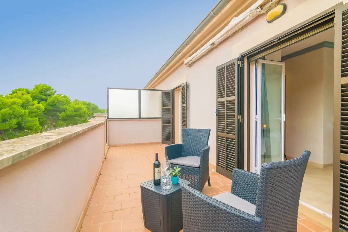 A terrace with wicker seating and an open sliding glass door.