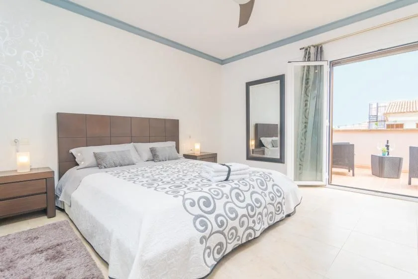 A bright bedroom with a large bed and sliding glass doors opening onto a terrace.