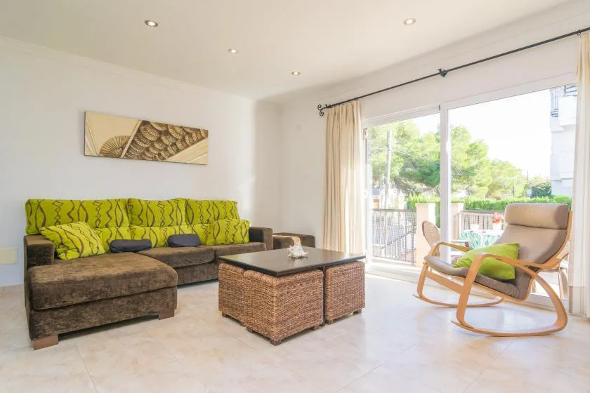 A bright living room with a green sofa, coffee table, and large glass doors.