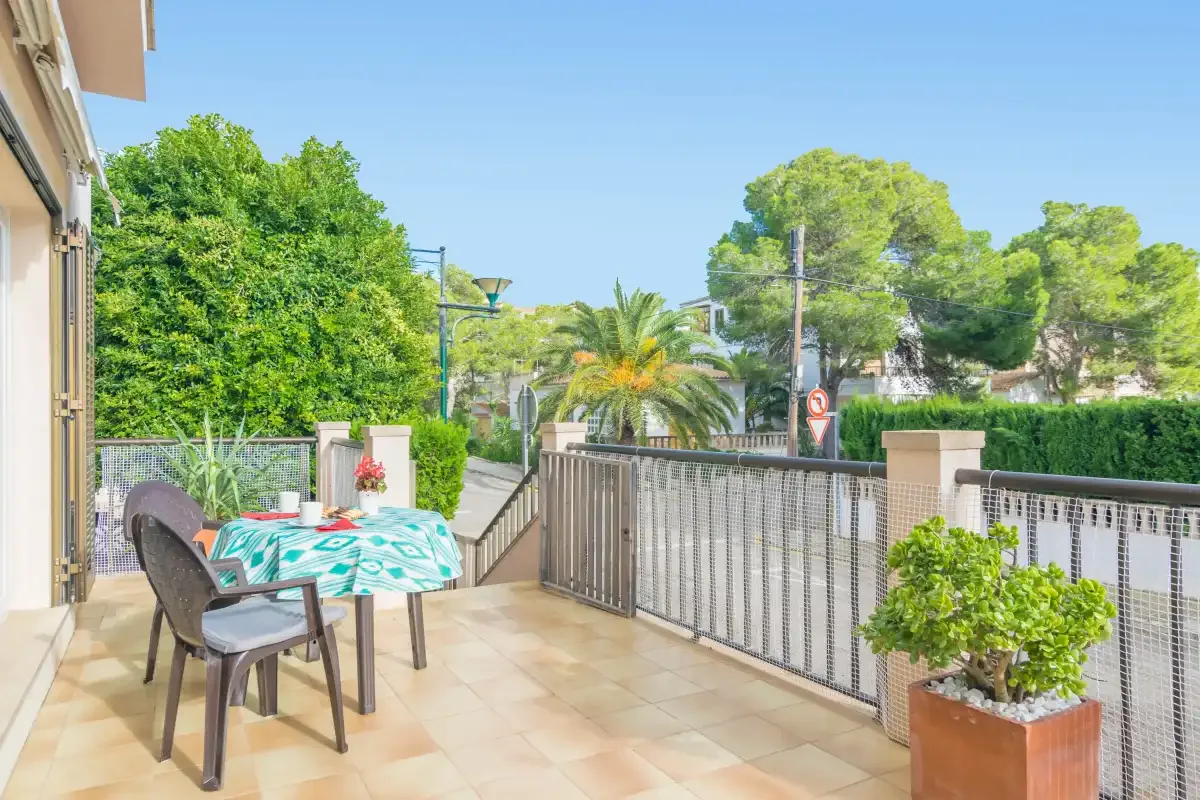 A tiled outdoor terrace has a dining table, seating, and potted plants.