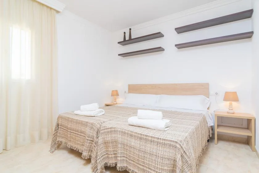 A bedroom with a bed, bedside tables, and floating wall shelves.