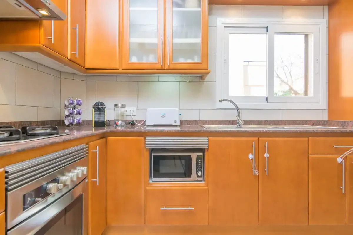 A kitchen with orange cabinets, a countertop, and a window.