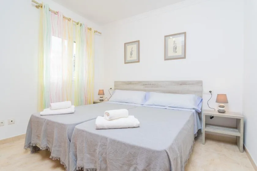A bright bedroom with a double bed, bedside tables, and colorful curtains.
