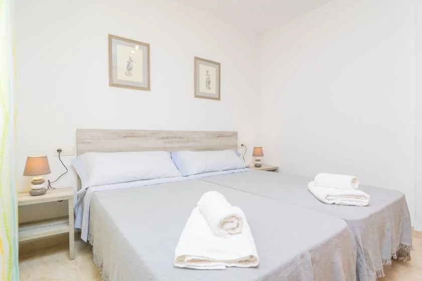 A bright bedroom with a neatly made bed and folded towels.