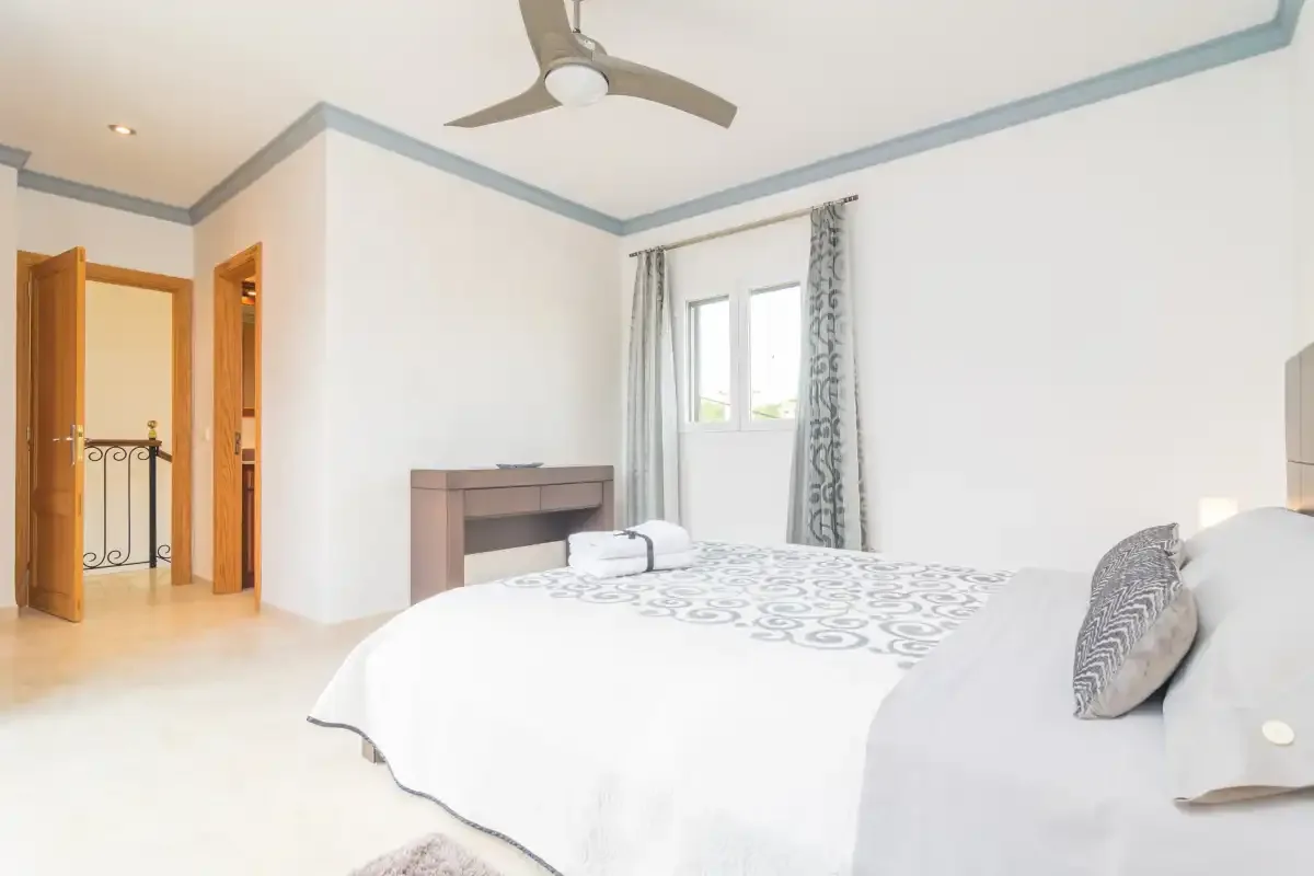 A bedroom with a large bed, a window, and a ceiling fan.