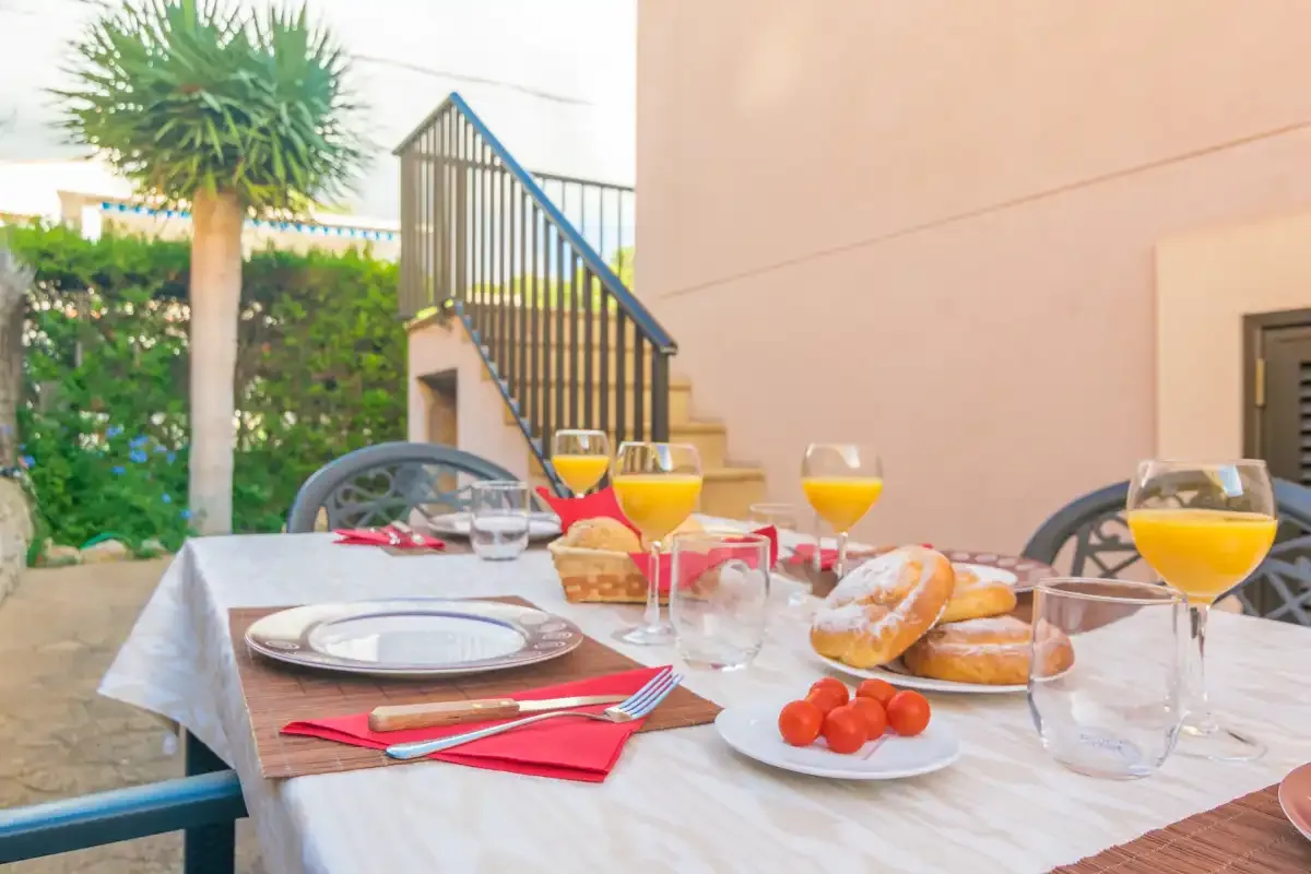 An outdoor dining area is set with plates, glasses, and food beside a staircase.
