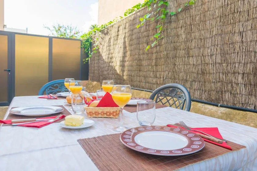 An outdoor dining table is set with plates, glasses, and drinks.