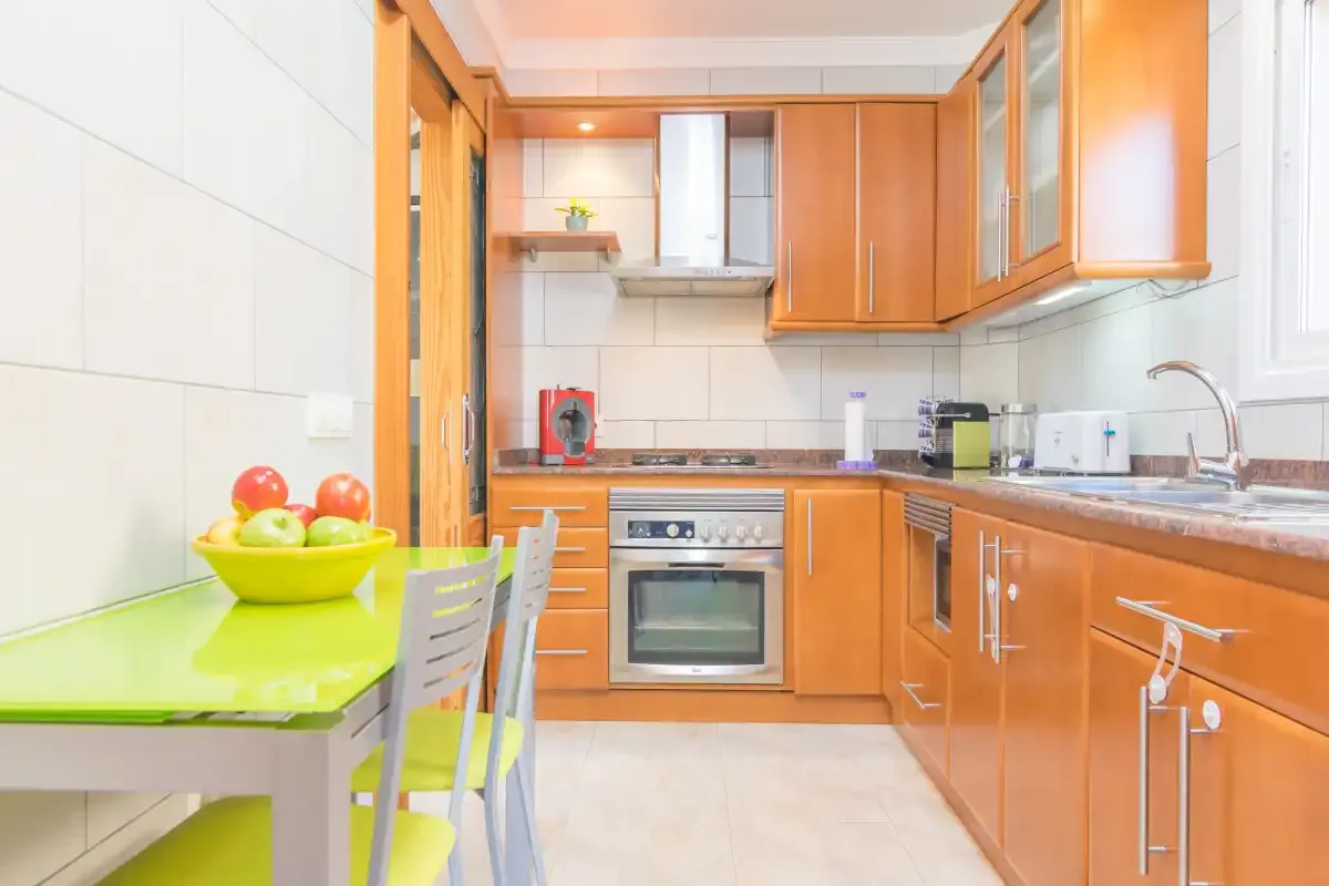 A bright kitchen with wooden cabinets, a countertop, and a small dining table.