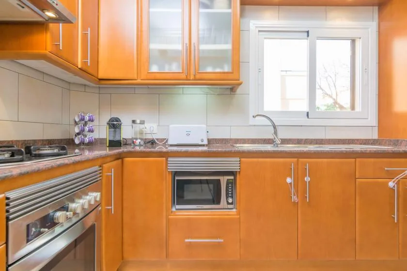 A kitchen with orange cabinets, a countertop, and a window above the sink.