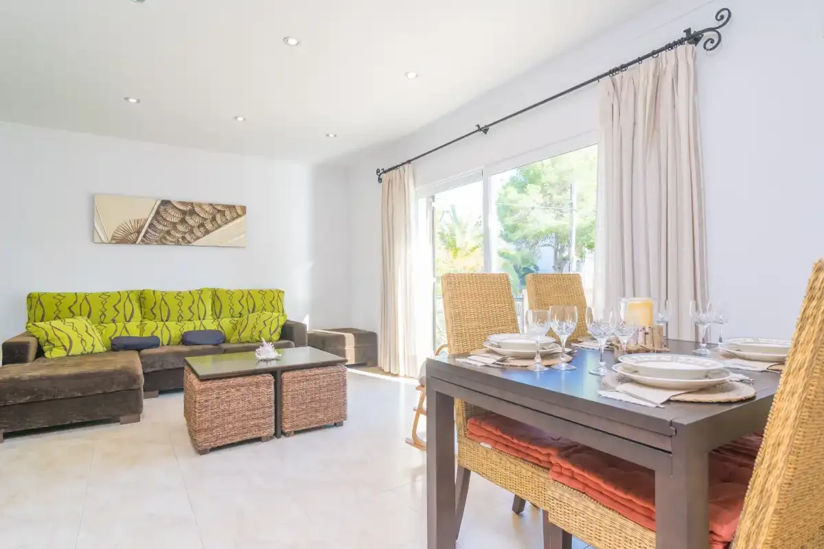 A bright living and dining area with seating beside a set dining table.