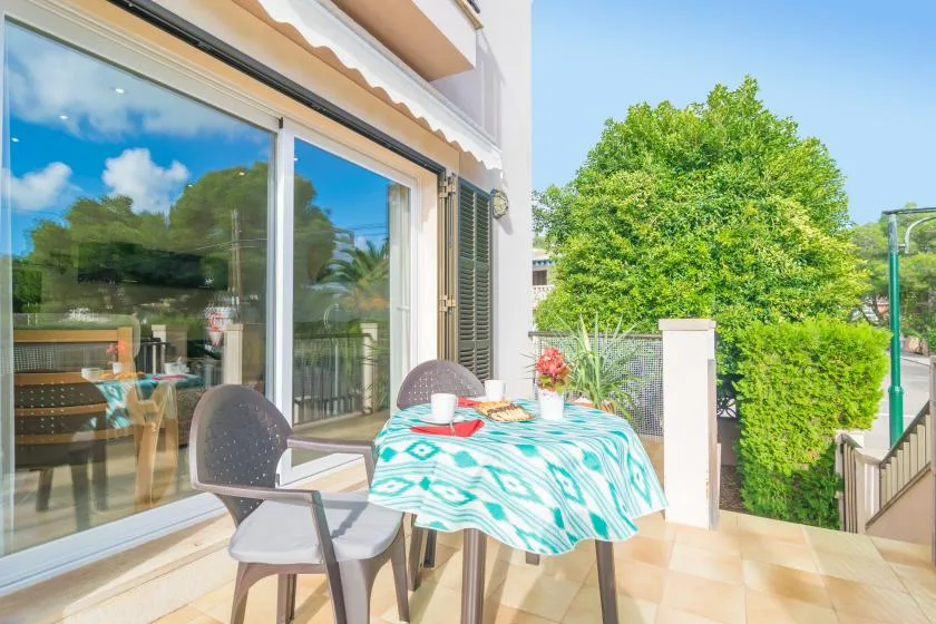 A patio dining area with a table and seating beside large glass doors.