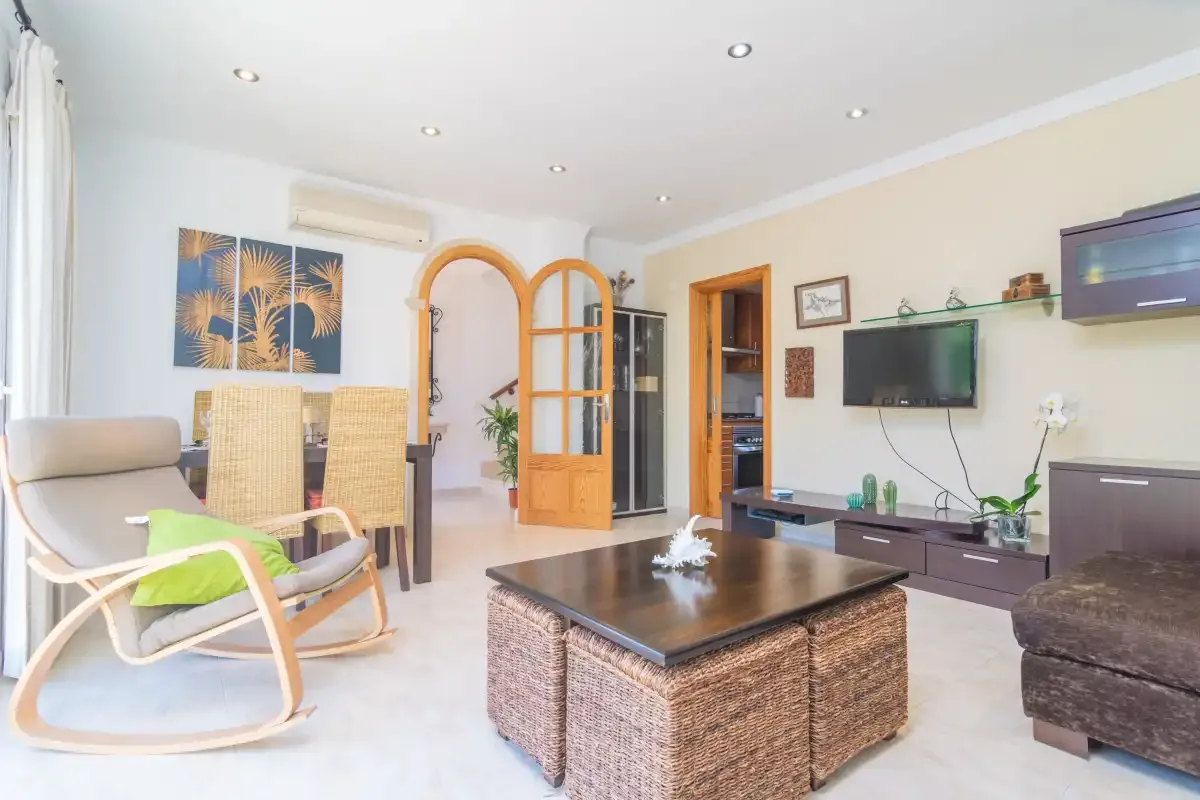 A bright living room with seating, a coffee table, and a television.