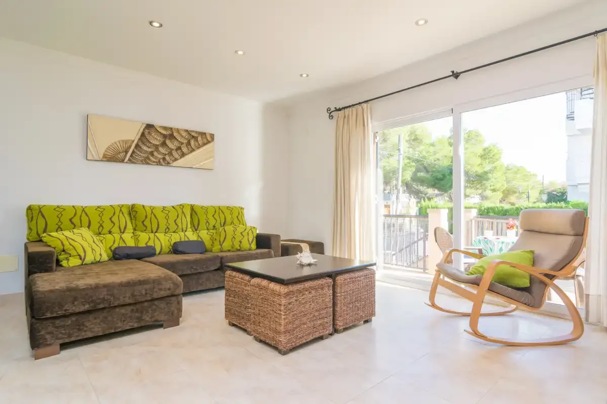 A living room with seating around a low coffee table and glass doors opening to a balcony.