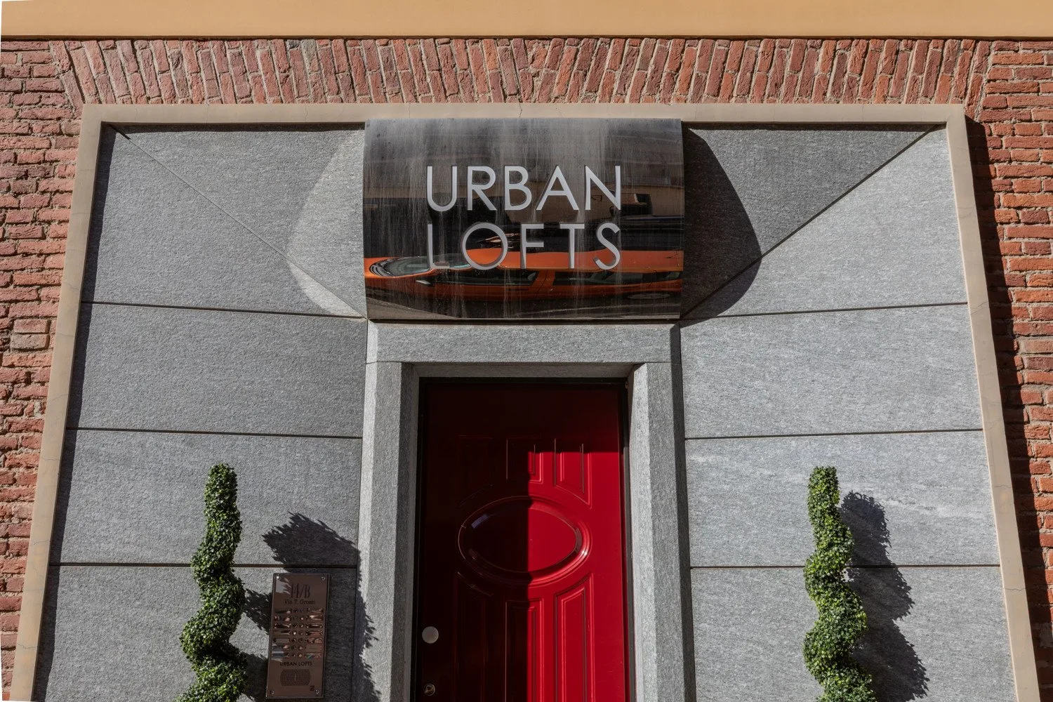 Entrada de un edificio con una puerta roja y un letrero encima.