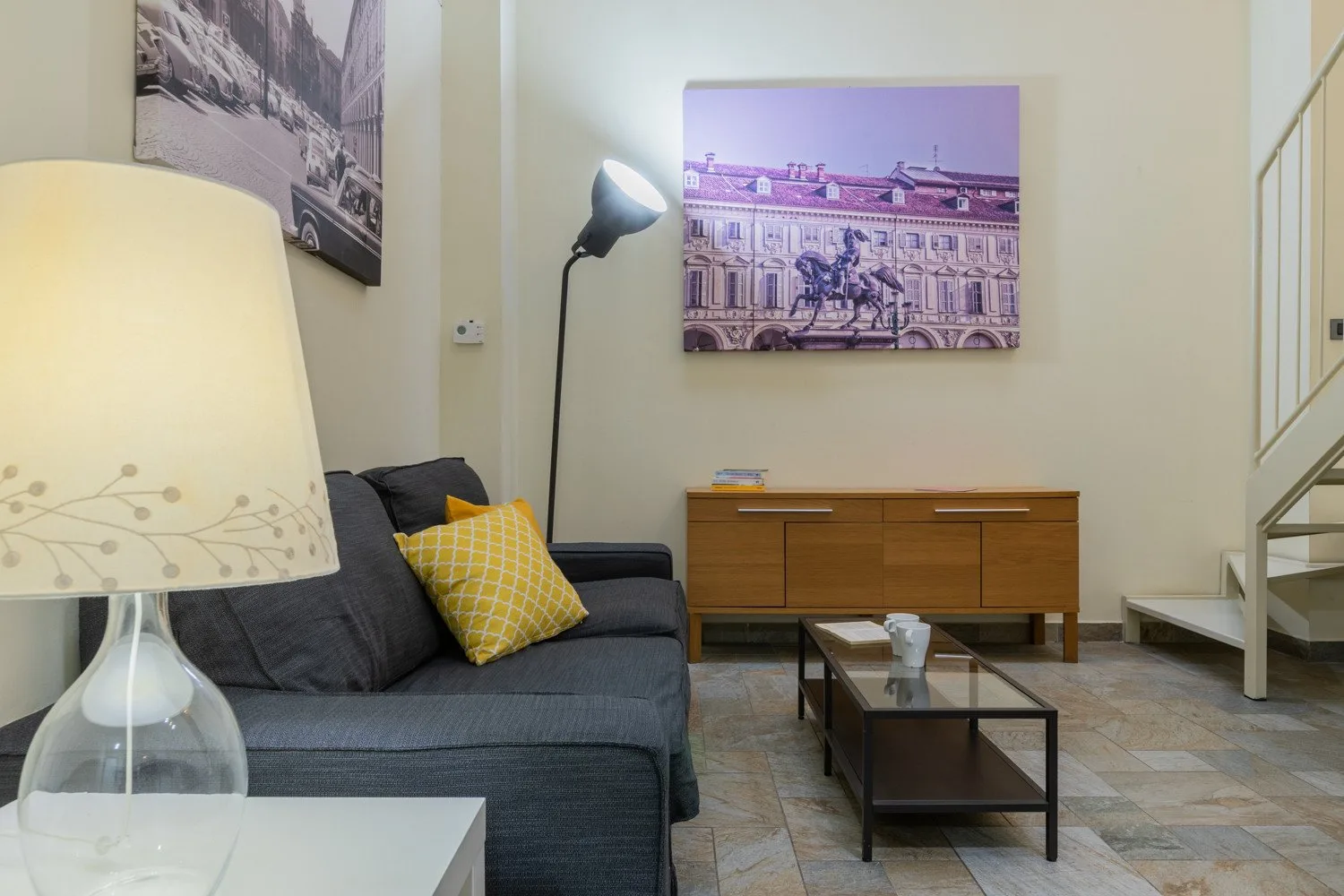 Una sala de estar con un sofá gris, una mesa de centro y un aparador de madera.