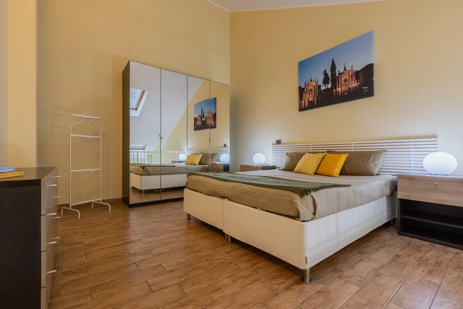 Un dormitorio con una cama, un armario con espejo y arte enmarcado.