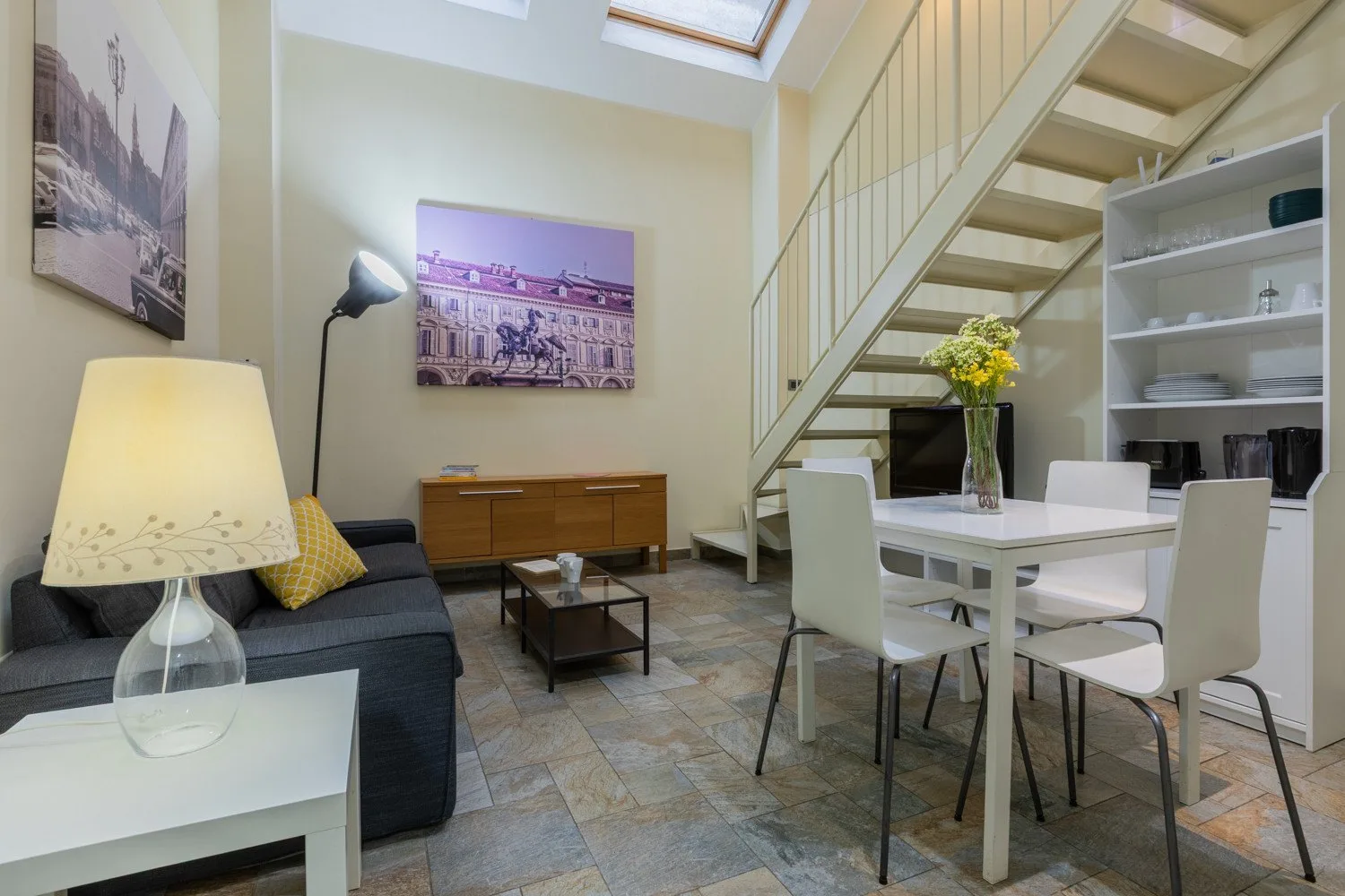 Una sala de estar y comedor con una mesa, asientos y una escalera.