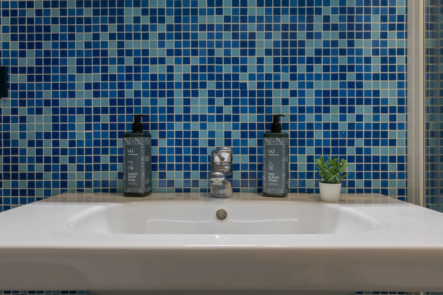 Un lavabo blanco está frente a una pared de mosaicos azules.