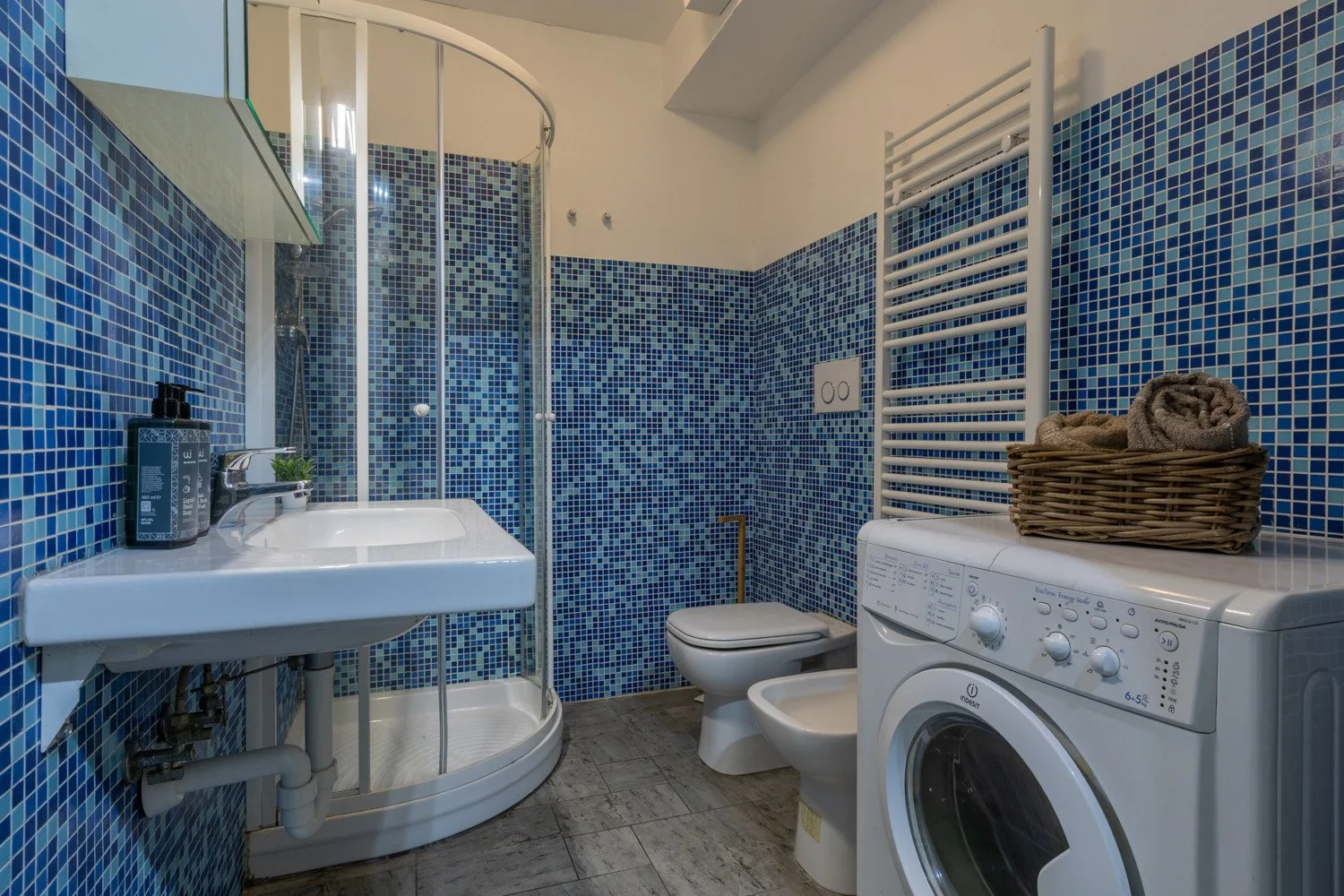Un baño alicatado con lavabo, ducha, inodoro y lavadora.