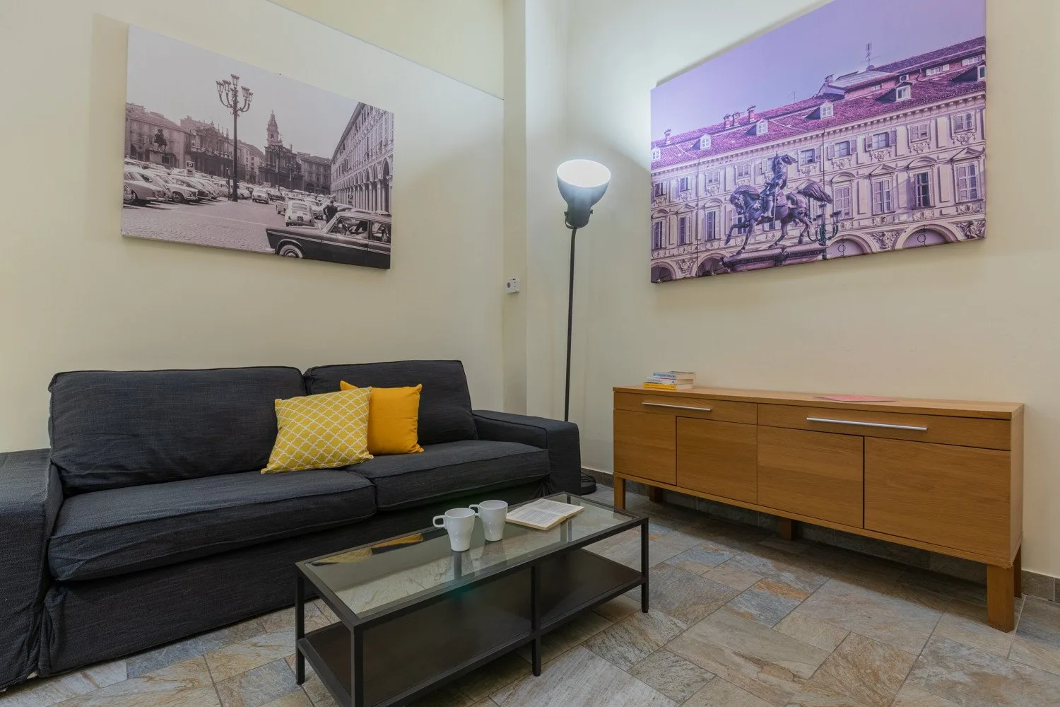 Una sala de estar con asientos oscuros, una mesa de centro y cuadros en la pared.