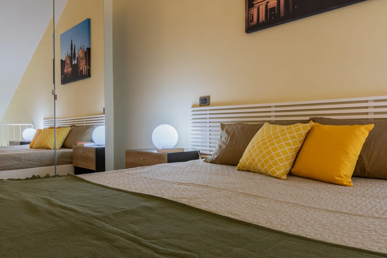 Un dormitorio con una cama tendida y cojines decorativos amarillos.