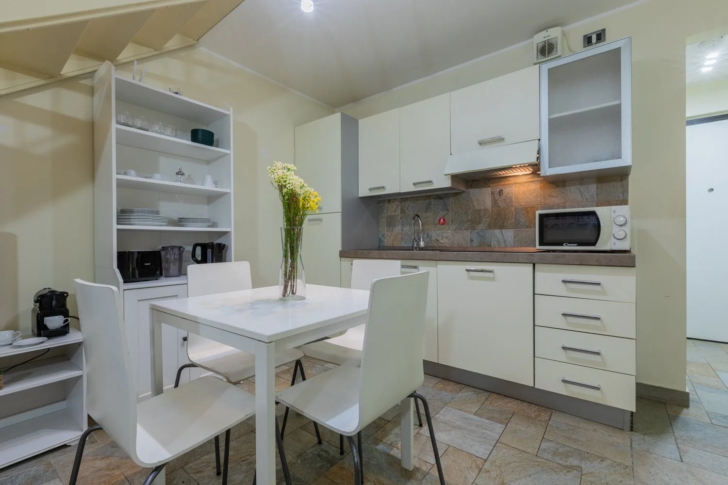 Una zona de comedor en la cocina con muebles blancos y una mesa rodeada de asientos.