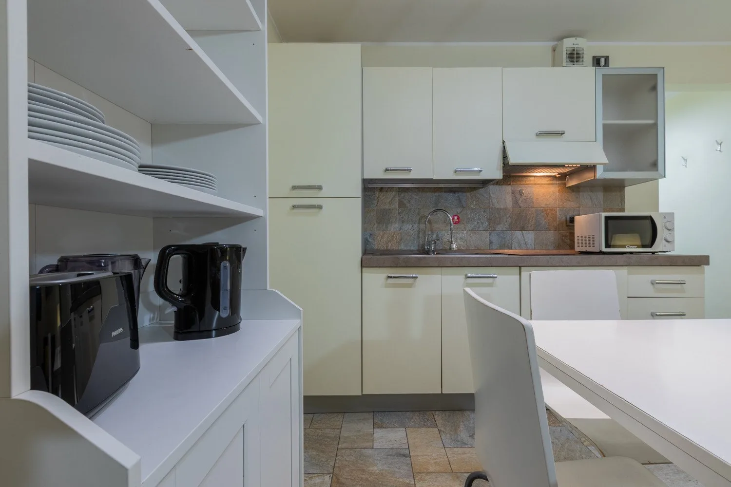 Una cocina moderna con gabinetes blancos, un salpicadero de azulejos y una mesa de comedor.