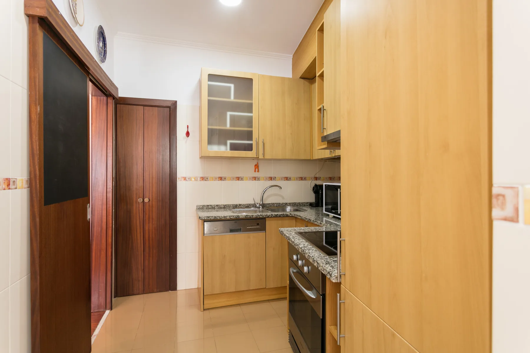 A compact kitchen with wooden cabinets and a granite countertop.
