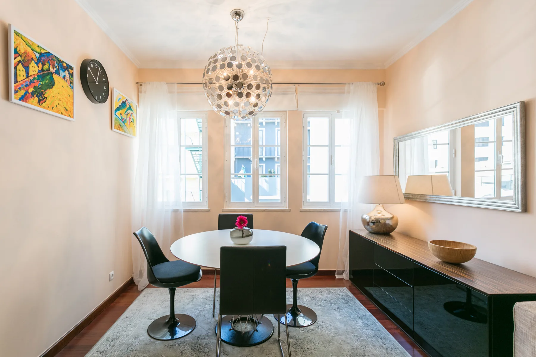 A dining area with a round table and large windows.