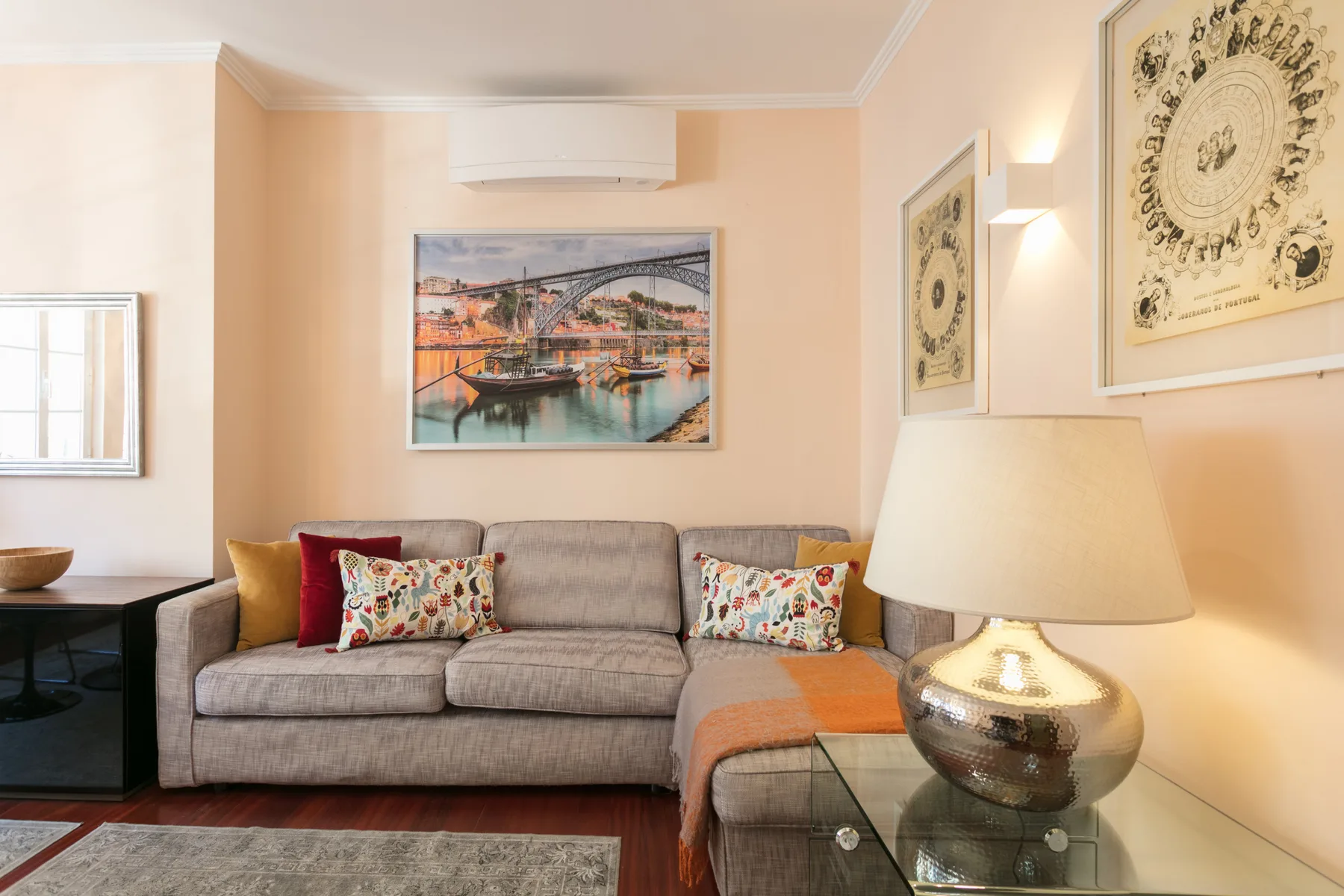 A living room with a sofa, framed artwork, and a glass coffee table.