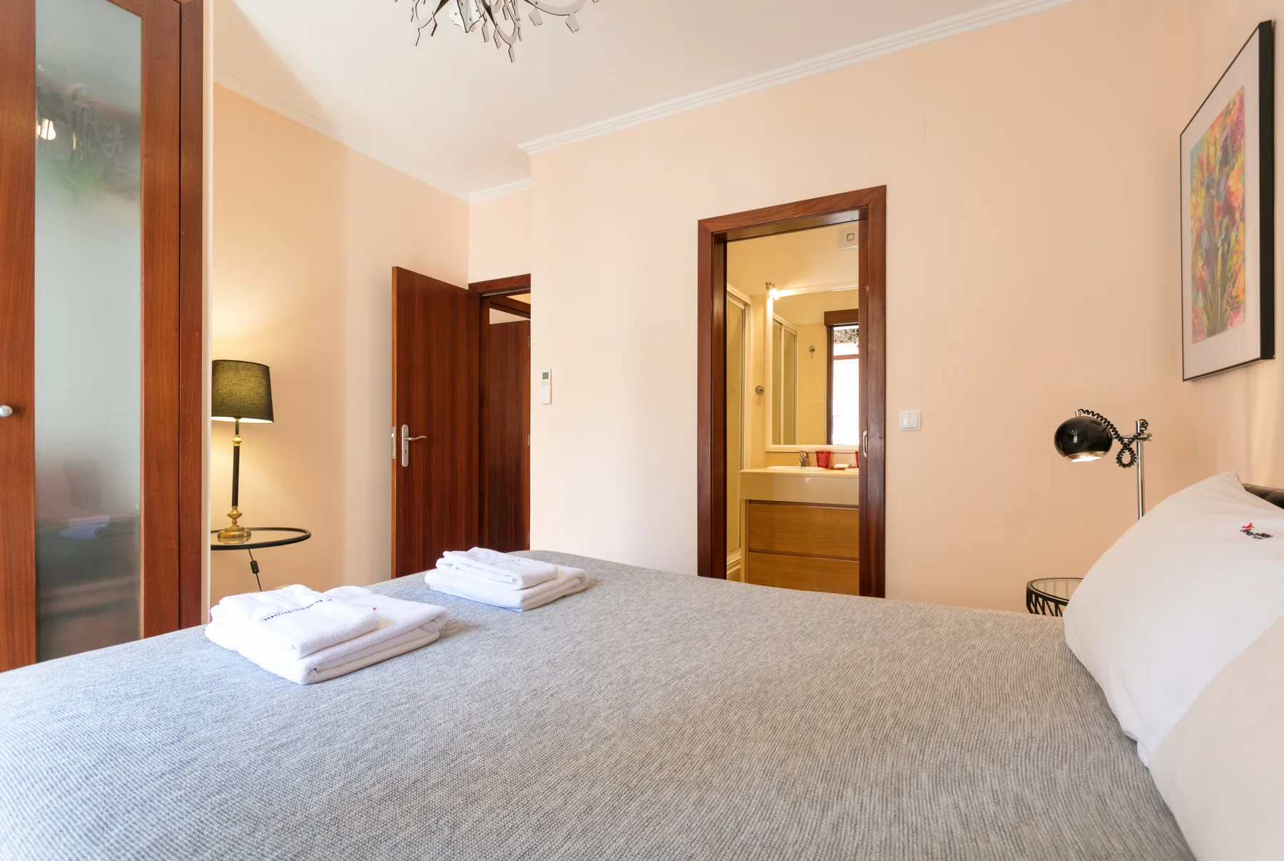 A bedroom with a neatly made bed and an open doorway to a bathroom.